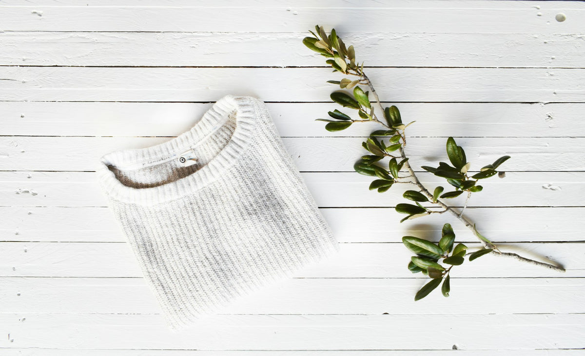 Cream knit rollneck folded on a pale surface